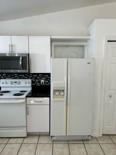 A white refrigerator stands in a kitchen next to a stove and oven.