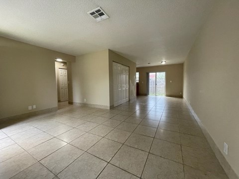 A spacious room with tiled flooring and two doors.