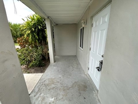 A white door is on the right side of a concrete room.