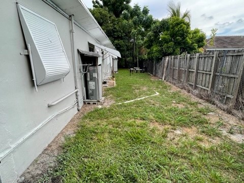 A backyard with a fence and a small tree.