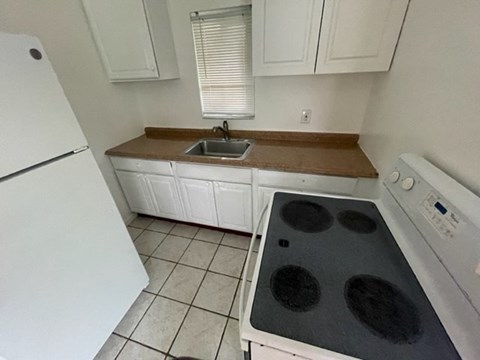A white kitchen with a black stove top.