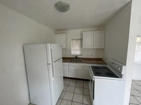 A kitchen with white appliances and cabinets.
