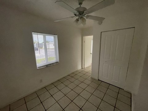 A room with a ceiling fan and tiled floor.