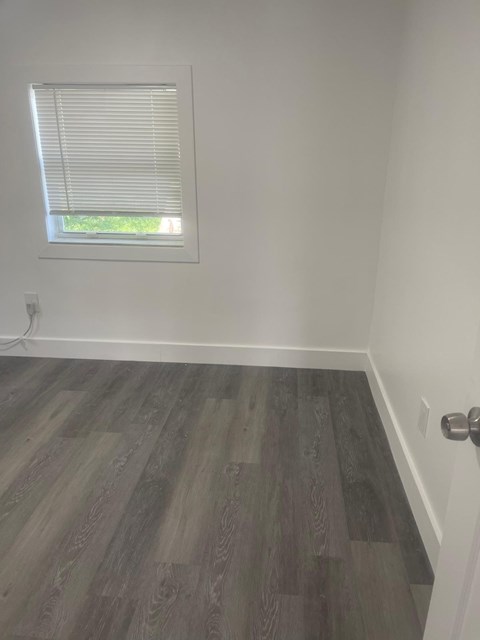 A room with a window and a wooden floor.