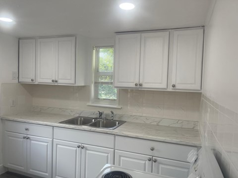 A kitchen with white cabinets and a marble countertop.