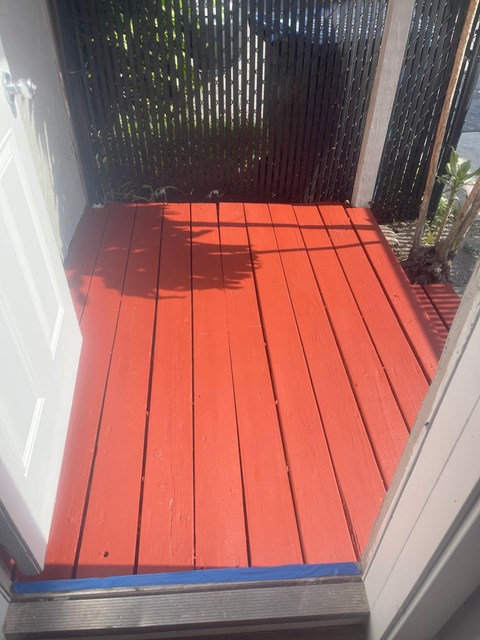A red wooden deck with a white door.