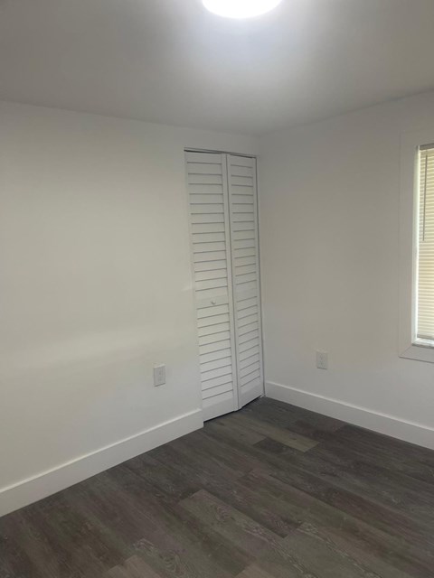 A room with a window and a wooden floor.
