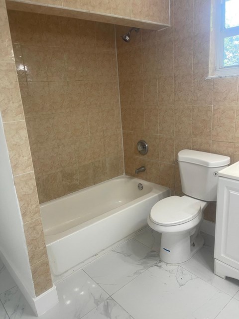 A white toilet sits next to a bathtub in a bathroom.