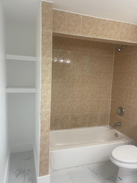 A white toilet sits next to a bathtub in a bathroom.