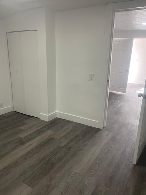 A room with a white door and a wooden floor.