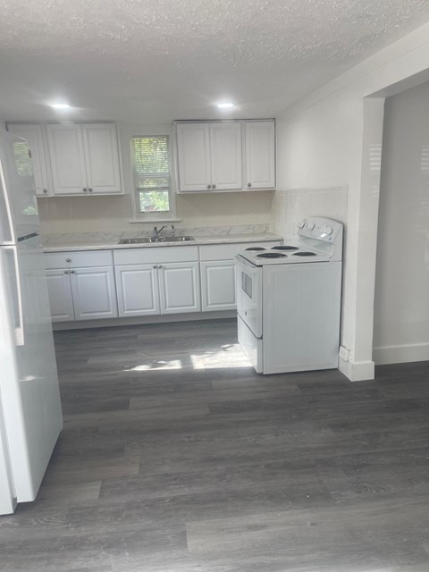 A kitchen with white cabinets and a white stove top oven.