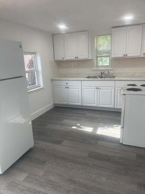 A kitchen with white appliances and cabinets.