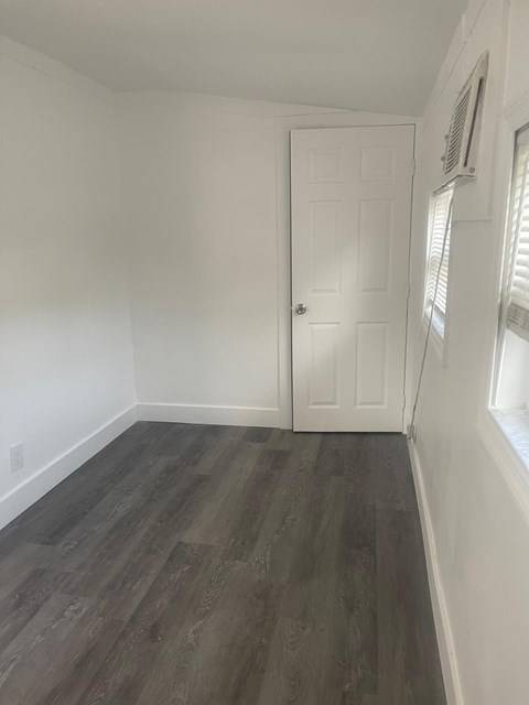 A room with a white door and a window with blinds.