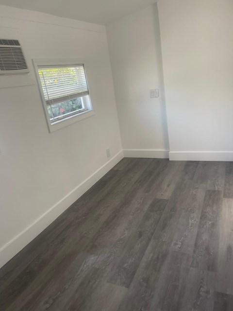 A room with a window and wooden flooring.