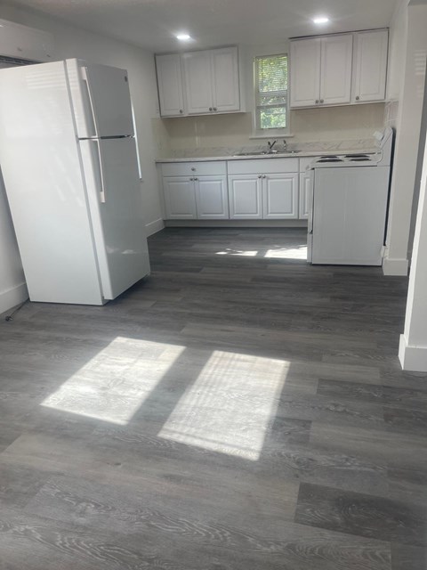 A kitchen with white appliances and cabinets.