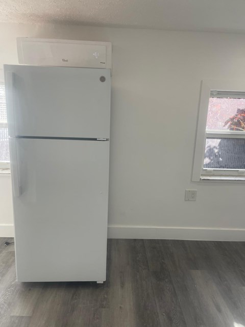 A white refrigerator in a room with a window.