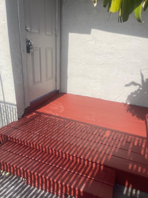 A red step outside a white door.