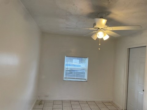 A room with a ceiling fan and a window.