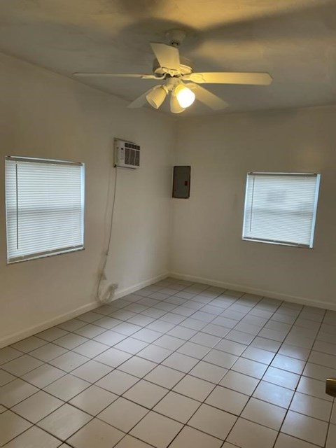A room with a ceiling fan and two windows.