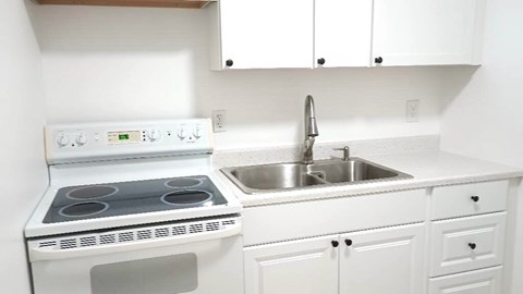 A white kitchen with a stove and sink.