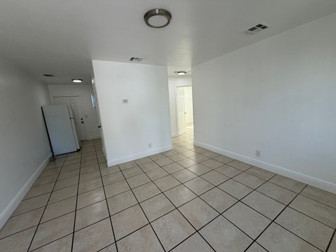 A spacious room with tiled flooring and white walls.