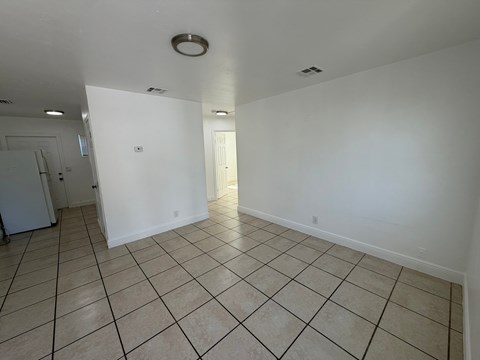 A spacious room with tiled flooring and white walls.