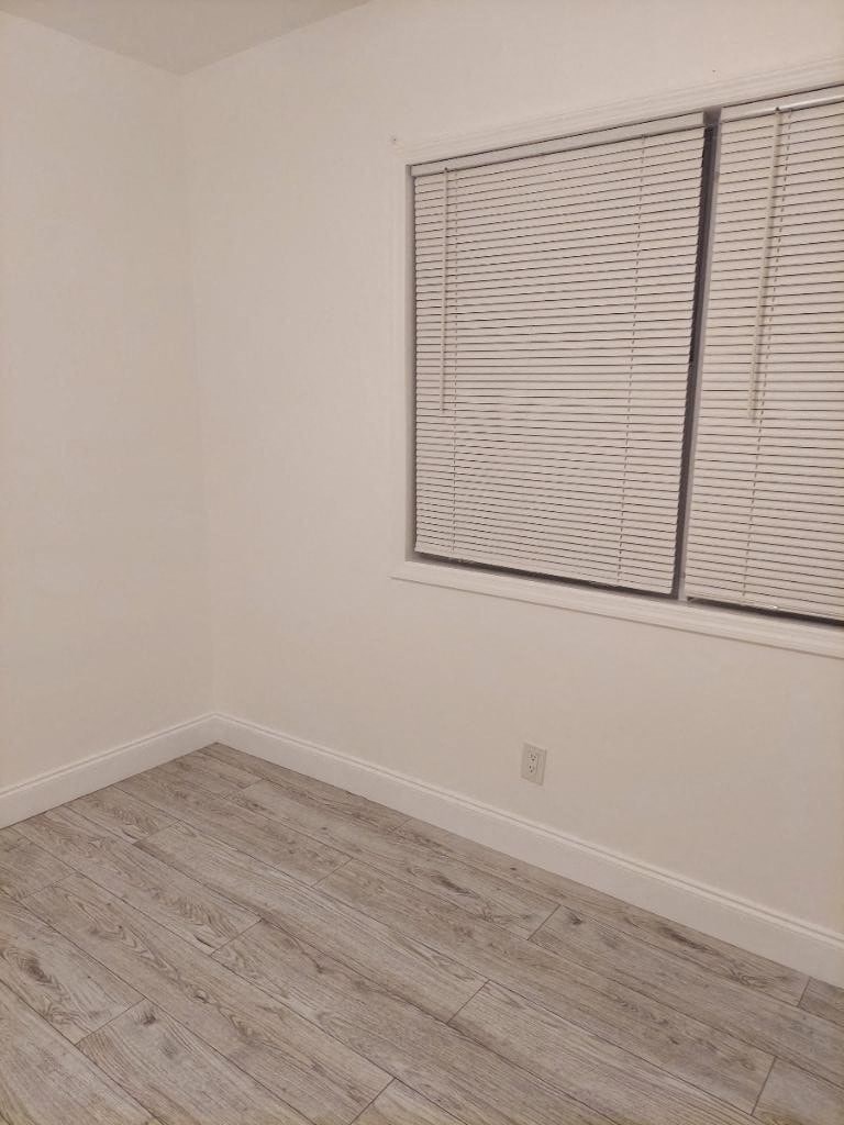 an empty room with a window and a wooden floor