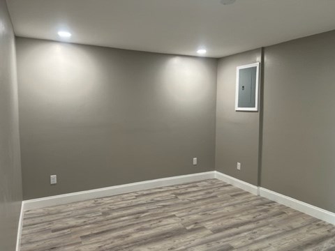 A room with wooden flooring and a grey wall.