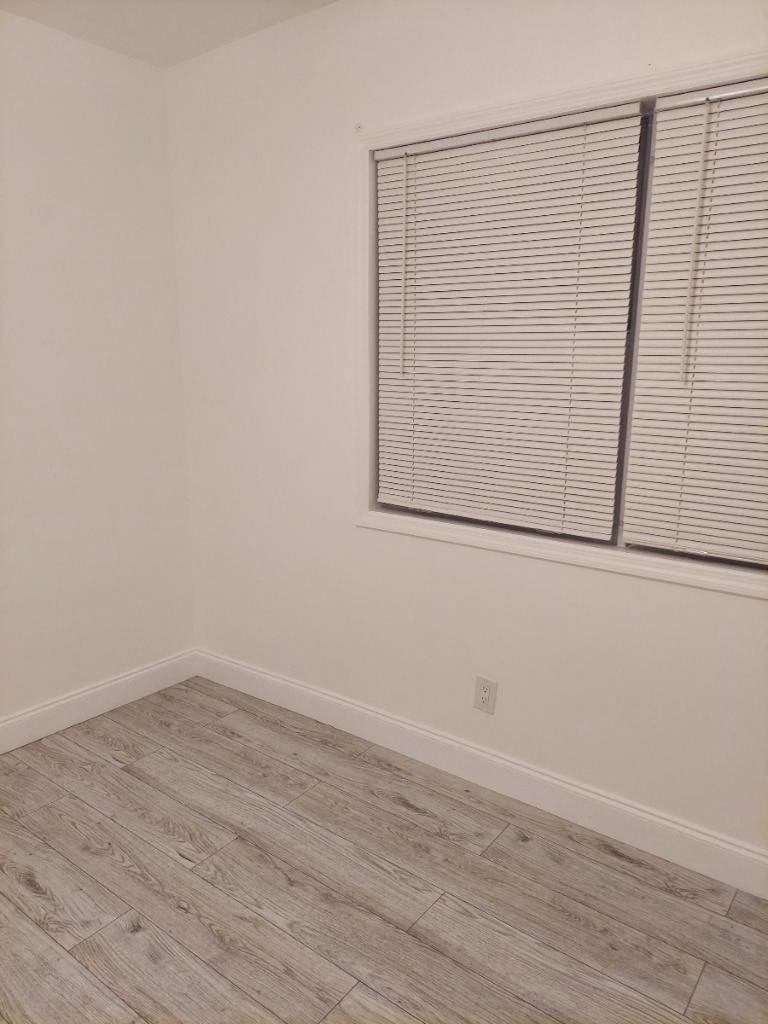 an empty room with a window and a wooden floor