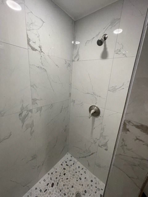a white tiled shower with a glass door