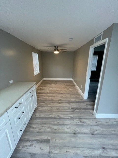 a empty kitchen with white cabinets and a ceiling fan