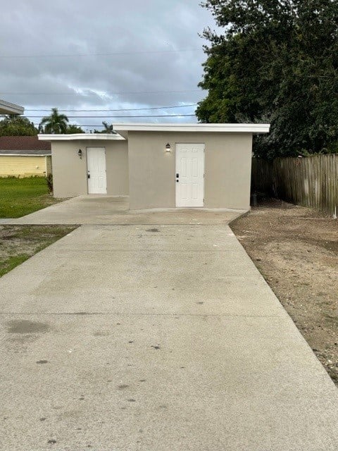A concrete pathway leads to a small building with two doors.