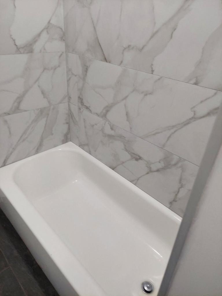 a white tub in a bathroom with marble walls