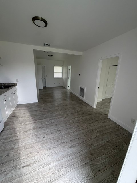 A spacious room with wooden flooring and white walls.