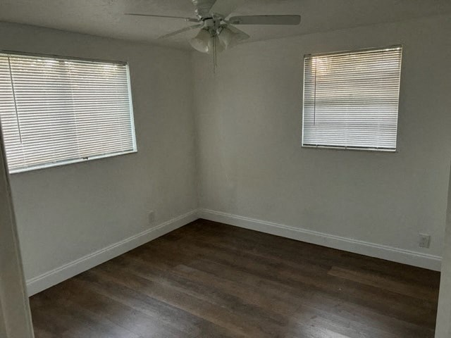 an empty room with a ceiling fan and two windows