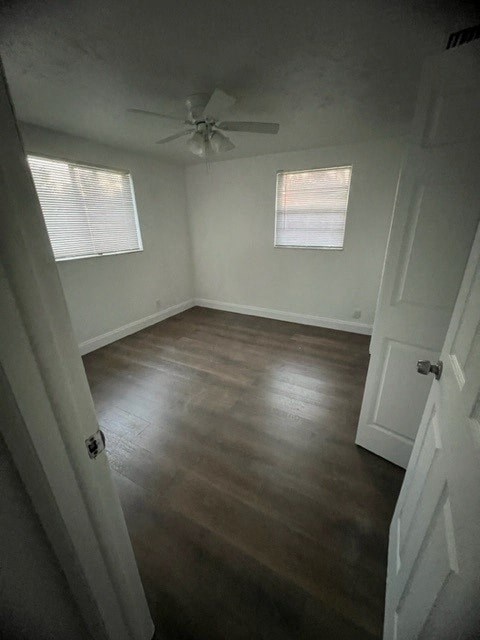 a empty room with wooden floors and a ceiling fan