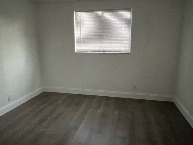 an empty room with a window and wooden floors