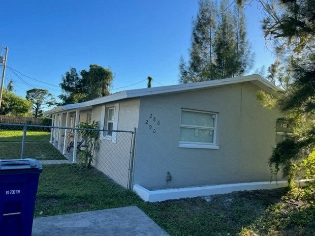 a small tan house with a yard and a fence