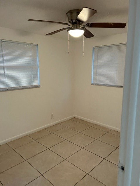 an empty room with a ceiling fan and a tiled floor