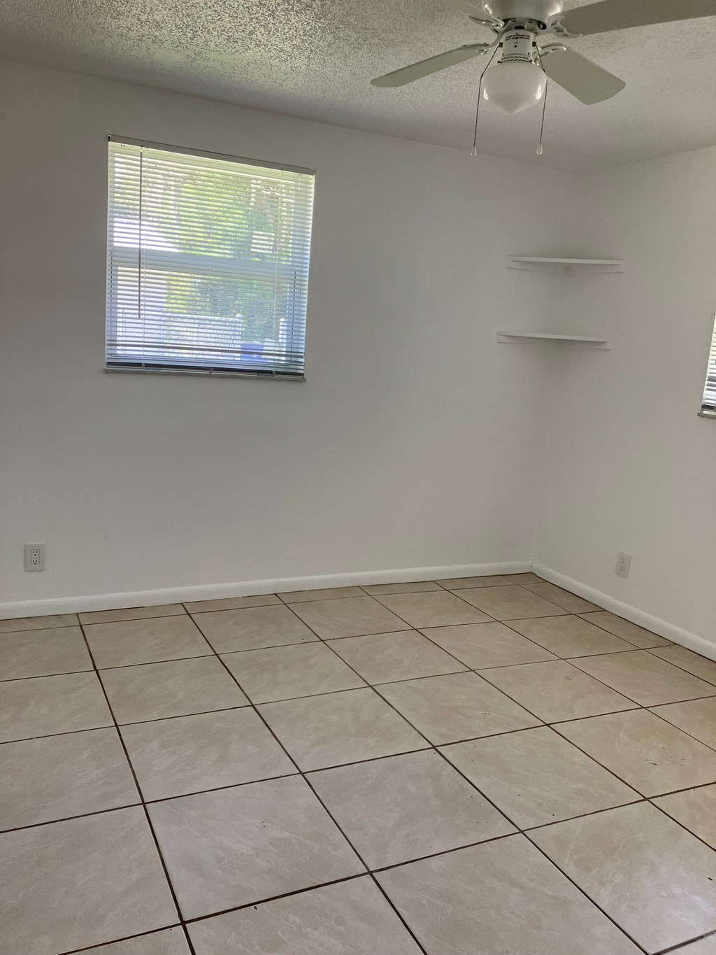 an empty living room with tiled floors and a window