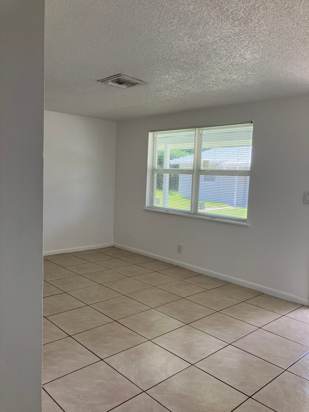an empty living room with a window and a tiled floor