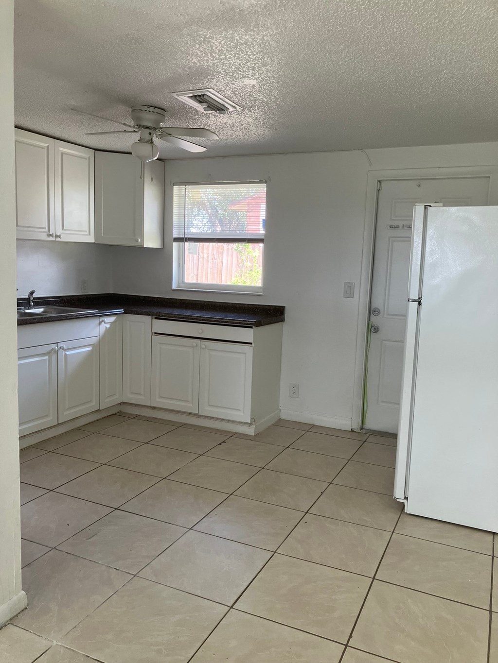 an empty kitchen with white cabinets and a refrigerator