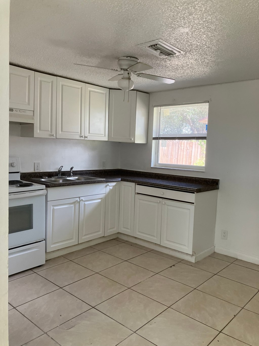 a kitchen with white cabinets and a sink and a window