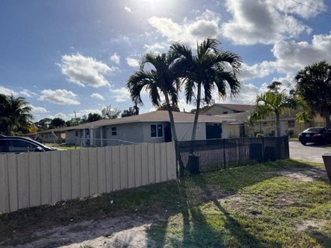 A sunny day with palm trees and a house in the background.