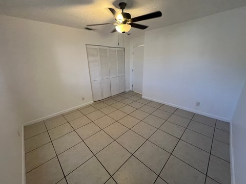 A room with a ceiling fan and tiled floor.