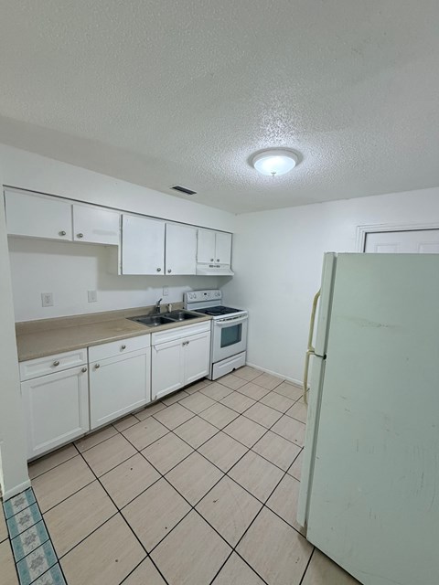 A kitchen with white cabinets and a white refrigerator.
