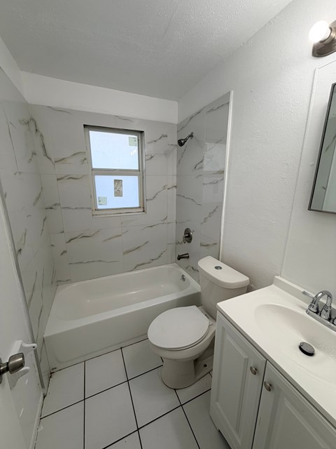 A white bathroom with a marble wall and a white toilet.