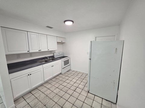 A kitchen with white cabinets and a white refrigerator.