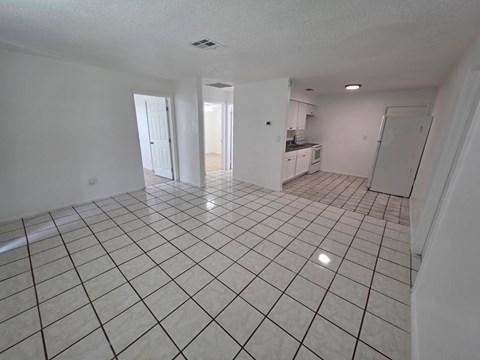 A spacious room with white tile flooring and white walls.