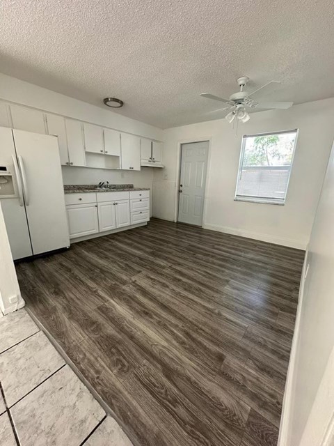 A kitchen with white cabinets and a wooden floor.